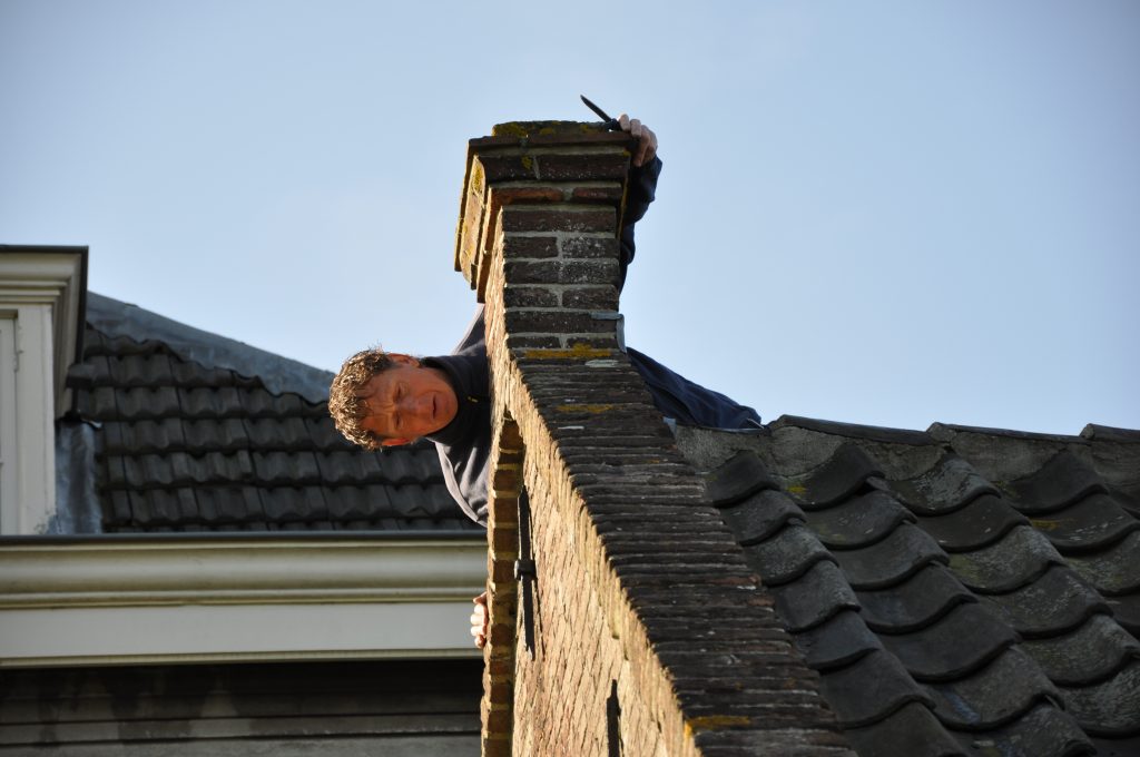 Een inspecteur van Monumentenwacht aan het werk op een dak.